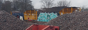 Two ballast hopper wagons behind large piles of ballast