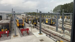 A number of outdoor stabling roads, with a number of metrocars occupying them as well as one Class 555 unit. A small building is visible on the left, next to two roads that end in buffers.