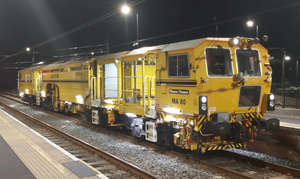 Yellow ballast tamper at a platform