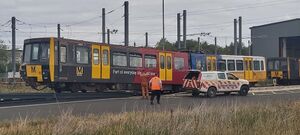 Metrocar 4001 being winched away from a shed and up a ramp, with an escort vehicle visible alongside it